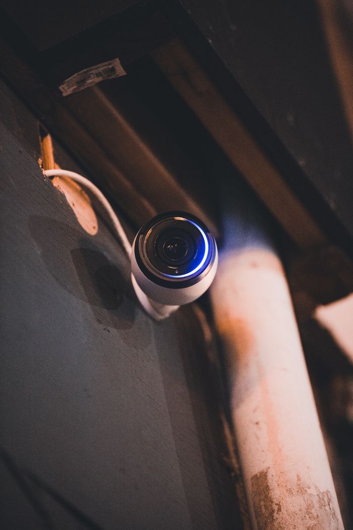 A security camera mounted on an indoor wall with ambient lighting.